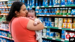 Yury Navas, 29, of Laurel, Md., kisses her two-month-old baby Jose Ismael Gálvez, while looking for formula at Superbest International Market in Laurel, Md., May 23, 2022. (AP Photo/Jacquelyn Martin)