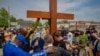 FILE - On May 21, 2022, a group prays at a memorial for victims of a shooting a week earlier at Tops Friendly Market in Buffalo, New York. The shooting was among the hate crimes in the U.S. in 2022.