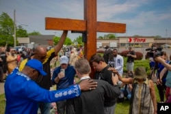 FILE - A group prays at the site of a memorial for the victims of the Buffalo supermarket shooting outside the Tops Friendly Market on May 21, 2022, in Buffalo, N.Y. (AP Photo/Joshua Bessex, File)