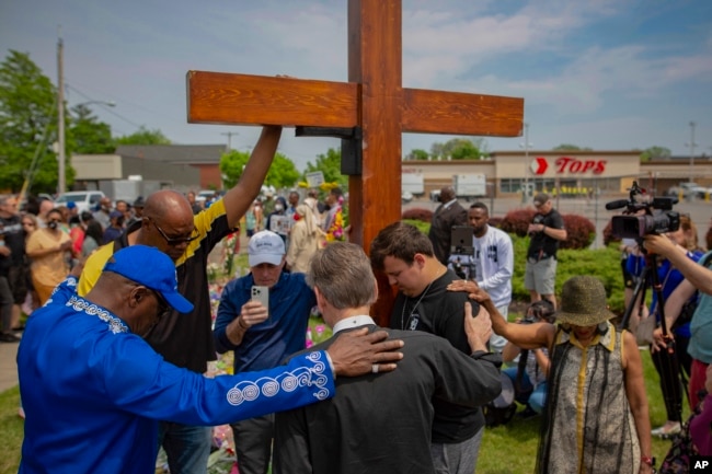 FILE - A group prays at the site of a memorial for the victims of the Buffalo supermarket shooting outside the Tops Friendly Market on May 21, 2022, in Buffalo, N.Y. (AP Photo/Joshua Bessex, File)