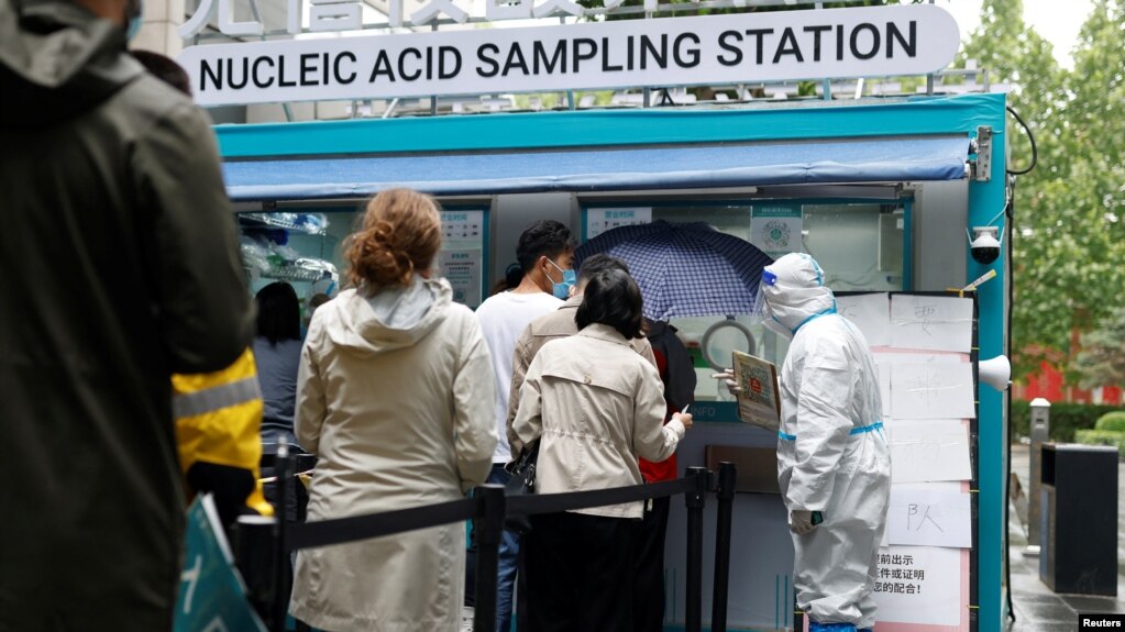 5月6日，北京市民冒雨在一流动新冠病毒核酸检测站前排队等候检测，一名身穿防护服的工作人员在维持秩序。-路透社照(photo:VOA)
