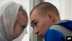 Russian Sgt. Vadim Shishimarin listens to his translator during a court hearing in Kyiv, Ukraine, May 23, 2022. The court sentenced the 21-year-old soldier to life in prison on Monday for killing a Ukrainian civilian, in the first war crimes trial held since Russia's invasion.