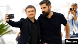 Romanian filmmaker Cristian Mungiu, left, and cast member Marin Grigore take a selfie as they pose at the 75th Cannes Film Festival, in Cannes, France, May 22, 2022. 