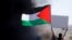 Seorang Palestina mengibarkan bendera Palestina saat protes anti-Israel atas kekerasan lintas perbatasan antara militan Palestina di Gaza dan militer Israel, 18 Mei 2021.