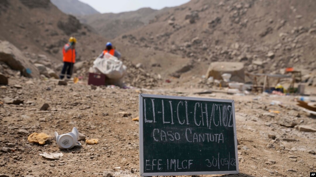 Un letrero colocado en el suelo marca el sitio antes del inicio de una excavación donde se encontraron víctimas de una masacre de escuadrones militares de la muerte en 1992 en Cineguilla, Perú, el lunes 30 de mayo de 2022.