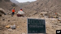 Un letrero colocado en el suelo marca el sitio antes del inicio de una excavación donde se encontraron víctimas de una masacre de escuadrones militares de la muerte en 1992 en Cineguilla, Perú, el lunes 30 de mayo de 2022.