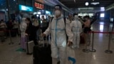 A traveller wearing protective overall gets through a health code check point at the train station, Tuesday, May 31, 2022, in Shanghai. Shanghai authorities say they will take major steps Wednesday toward reopening China's largest city after a two-month C