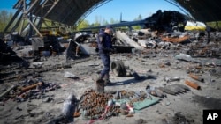 A Ukrainian sapper searches for unexploded explosives at the remains of the Antonov An-225, the world's biggest cargo aircraft destroyed during recent fighting between Russian and Ukrainian forces, at the Antonov airport in Hostomel, on the outskirts of Kyiv, May 5, 2022.