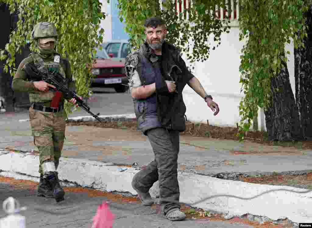 A wounded service member of Ukrainian forces who had surrendered after weeks holed up at Azovstal steel works is escorted by a member of the pro-Russian military at a detention facility in the course of Ukraine-Russia conflict in the settlement of Olenivka in the Donetsk Region, Ukraine