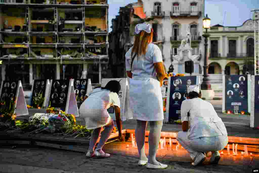 Enfermeras encienden velas durante la vigilia por las víctimas del accidente del Hotel Saratoga en La Habana, el 13 de mayo de 2022.