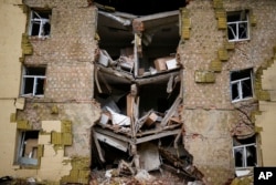 Puing-puing tergantung dari sebuah bangunan tempat tinggal yang rusak berat dalam pemboman Rusia di Bakhmut, Ukraina timur, Ukraina timur, 28 Mei 2022. (Foto: AP)