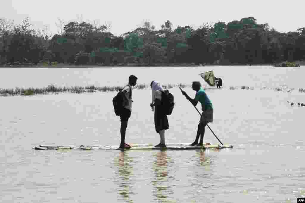 A man transports school students on a bamboo raft across a flooded area following heavy rains in Sylhet, Bangladesh.