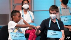 Sulayman Abdirahman, 12, from Roxbury, Massachusetts, left, gets a fist bump from Aaron Kuebler, 12, from Oviedo, Florida, after Abdirahman advanced to the next round, while competing during the Scripps National Spelling Bee.