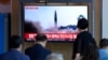 People watch a TV screen showing a news program reporting about North Korea's missile launch with file footage, at a train station in Seoul, South Korea, , May 25, 2022