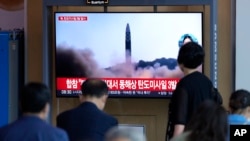 People watch a TV screen showing a news program reporting about North Korea's missile launch with file footage, at a train station in Seoul, South Korea, , May 25, 2022