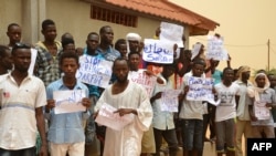 Un groupe de migrants tient des banderoles pour protester contre la violence contre les réfugiés lors de la visite du Haut-Commissaire des Nations Unies pour les réfugiés Filippo Grandi à Agadez le 21 juin 2018