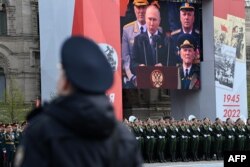Sebuah layar menunjukkan Presiden Rusia Vladimir Putin memberikan pidato saat prajurit berbaris di Lapangan Merah selama parade militer Hari Kemenangan di pusat kota Moskow pada 9 Mei 2022. (Foto: AFP/Kirill KUDRYAVTSEV)
