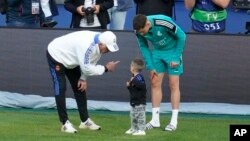 Real Madrid's head coach Carlo Ancelotti, left, speaks to Benicio, the son of Federico Valverde, right, during a training session.