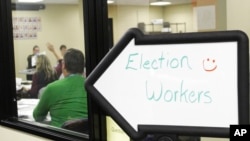 Elections workers, seen through a window, review ballots at the Clackamas County Elections Office, May 19, 2022, Oregon City, Ore.