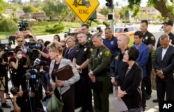 Laguna Woods Mayor Carol Moore, front left at podium, and Orange County Board of Supervisor, Lisa Barlett, right, surrounded by law enforcement officers, hold a press conference outside the grounds og Geneva Presbyterian Church in Laguna Woods, Calif., Ma