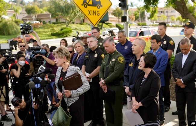 Laguna Woods Mayor Carol Moore, front left at podium, and Orange County Board of Supervisor, Lisa Barlett, right, surrounded by law enforcement officers, hold a press conference outside the grounds og Geneva Presbyterian Church in Laguna Woods, Calif., Ma
