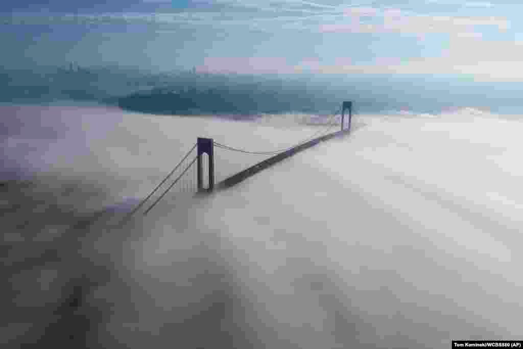 The Manhattan skyline is visible, upper left, as cars traverse the Verrazzano-Narrows Bridge, connecting the Brooklyn and Staten Island boroughs of New York, while fog covers the waters of the Atlantic Ocean and New York Bay, Monday morning, May 16, 2022.