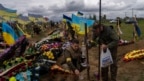 Dos guardias nacionales visitan la tumba de un soldado fallecido en el cementerio de Kharkiv, este de Ucrania, el 22 de mayo de 2022.