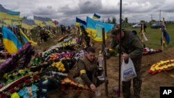 Dos guardias nacionales visitan la tumba de un soldado fallecido en el cementerio de Kharkiv, este de Ucrania, el 22 de mayo de 2022.