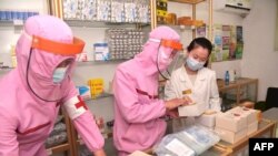 Personel medis dari Pasukan Tentara Korea Utara, yang mengenakan pakaian pelindung, mendistribusikan obat ke sebuah apotek di Pyongyang, pada 31 Mei 2022. (Foto: KCNA via KNS/AFP)