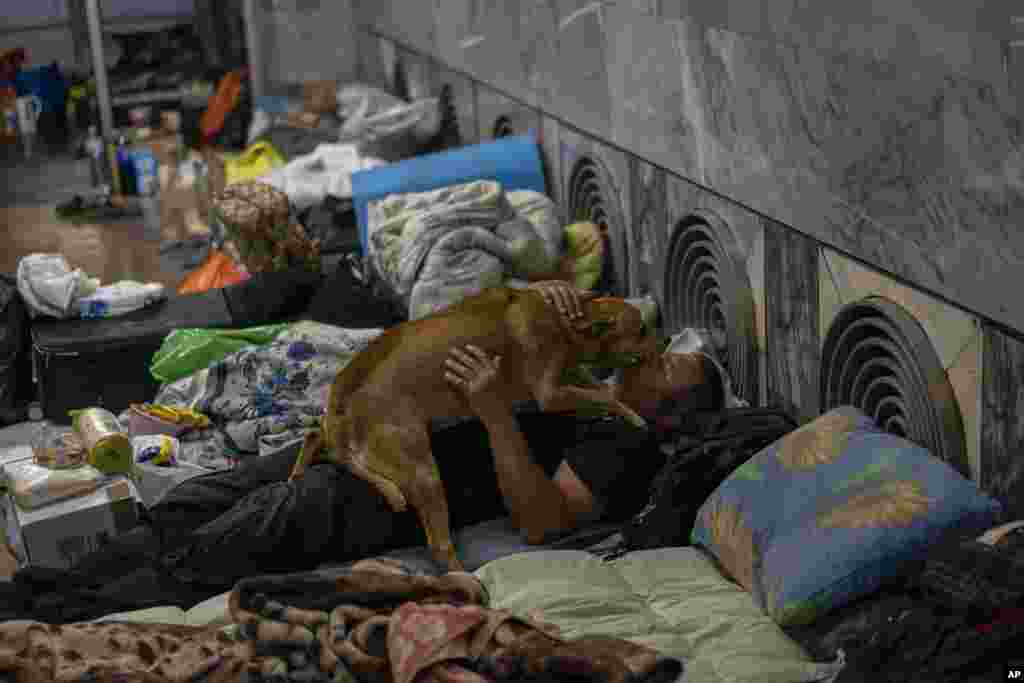 Un hombre acaricia a su perro en el metro de la ciudad de Kharkiv, en el este de Ucrania, el jueves 19 de mayo de 2022. (Foto AP/Bernat Armangue)