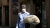 FILE: An Iranian man holds stacks of bread as he walks along a street in Tehran, Iran, May 1, 2022.
