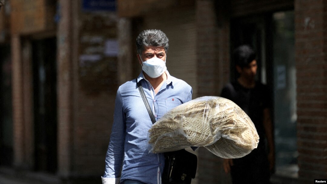 FILE: An Iranian man holds stacks of bread as he walks along a street in Tehran, Iran, May 1, 2022.