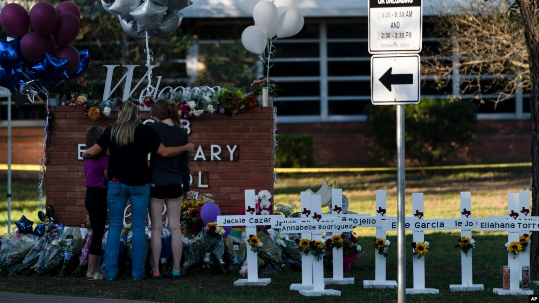 A family pays their respects next to crosses bearing the names of Tuesday's shooting victims at Robb Elementary School in Uvalde, Texas, May 26, 2022. (AP Photo/Jae C. Hong)

