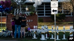 A family pays their respects next to crosses bearing the names of Tuesday's shooting victims at Robb Elementary School in Uvalde, Texas, May 26, 2022. (AP Photo/Jae C. Hong)
