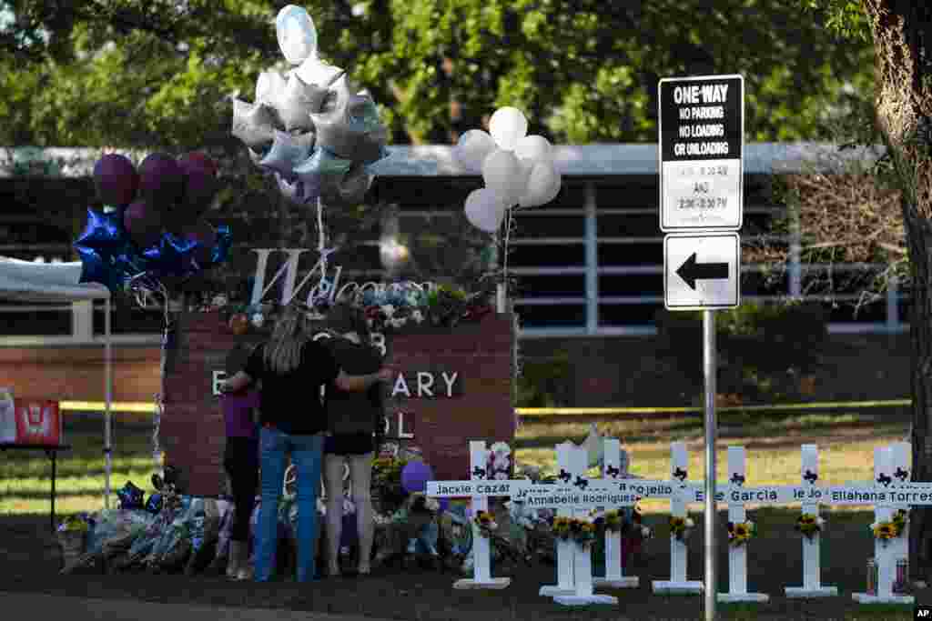 A family pays their respects next to crosses bearing the names of Tuesday&#39;s shooting victims at Robb Elementary School in Uvalde, Texas.
