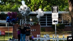 Sebuah keluarga memberikan penghormatan di sebelah salib bertuliskan nama-nama korban penembakan yang terjadi pada hari Selasa di Sekolah Dasar Robb di Uvalde, Texas, 26 Mei 2022. (Foto: AP)