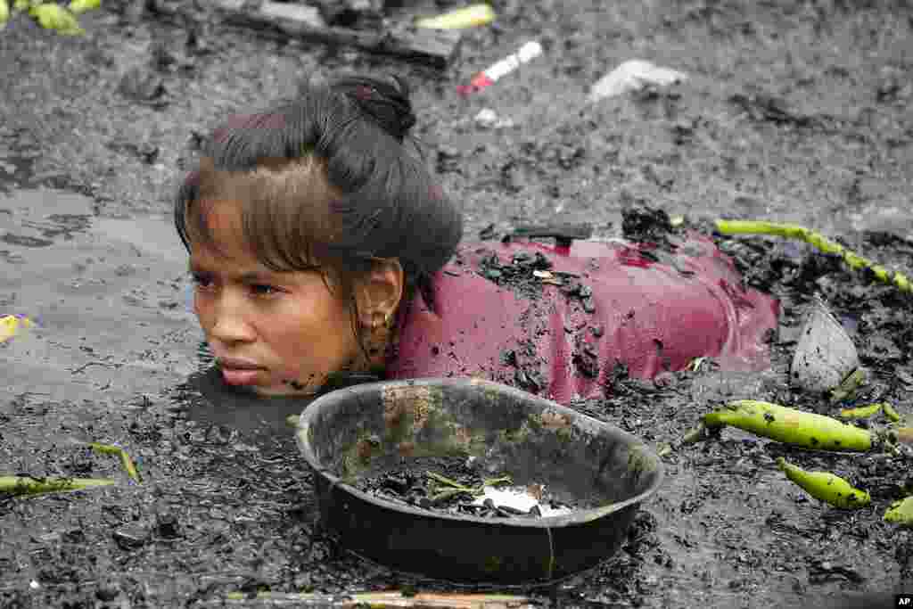 A woman searches for nails and other metal scraps from remains of burned houses that were gutted during a fire at a poor bayside village in the district of Tondo, Manila, Philippines.