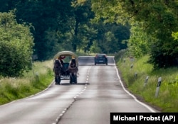 Horse breeder Stephanie Kirchner drives her horse-drawn carriage down a road near her hometown of Schupbach, Germany, May 19, 2022. (AP Photo/Michael Probst)