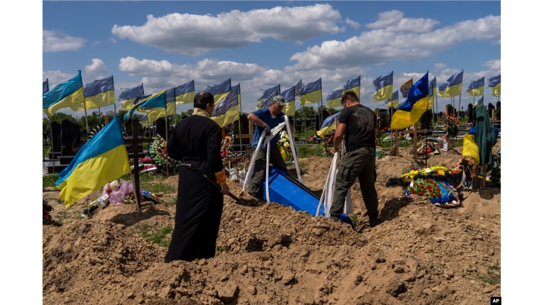 Petugas menurunkan peti mati prajurit Ukraina Oleksander Matyukhin, 32, di Kharkiv, Ukraina timur, Senin, 23 Mei 2022. (Foto: AP/Bernat Armangue)