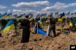 Petugas menurunkan peti mati prajurit Ukraina Oleksander Matyukhin, 32, di Kharkiv, Ukraina timur, Senin, 23 Mei 2022. (Foto: AP/Bernat Armangue)