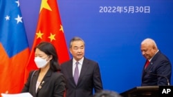 China's Foreign Minister Wang Yi, center, appears on stage at the Pacific Islands Foreign Ministers' meeting with Fiji's Prime Minister Frank Bainimarama, May 30, 2022, in Suva, Fiji.