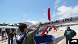 A young man looks at the Bayraktar TB2 drone, manufactured by Turkey's Baykar, as it is presented during the opening of the aerospace and technology festival 'Teknofest Azerbaijan' at Baku Crystal Hall in Baku, on May 27, 2022. 