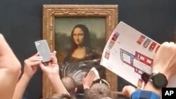 Un guardia de seguridad limpia crema de un pastel arrojado sobre el cristal que protege a la Mona Lisa en el Museo del Louvre en París, el 29 de mayo de 2022.