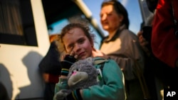 FILE - A child and her family who fled from Mariupol arrive at a reception center for displaced people in Zaporizhzhia, Ukraine, May 8, 2022.