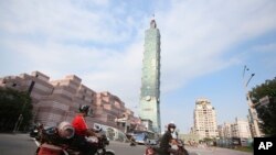FILE - People ride past Taipei 101 building in Taipei, Taiwan, Saturday, May 15, 2021. A strong earthquake struck off the east coast of Taiwan on Monday, shaking buildings in the capital, Taipei.