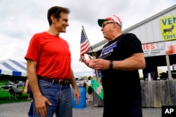FILE - Mehmet Oz, a Republican candidate for U.S. Senate in Pennsylvania, meets with an attendee during a visit to a car show in Carlisle, Pa., May 14, 2022.