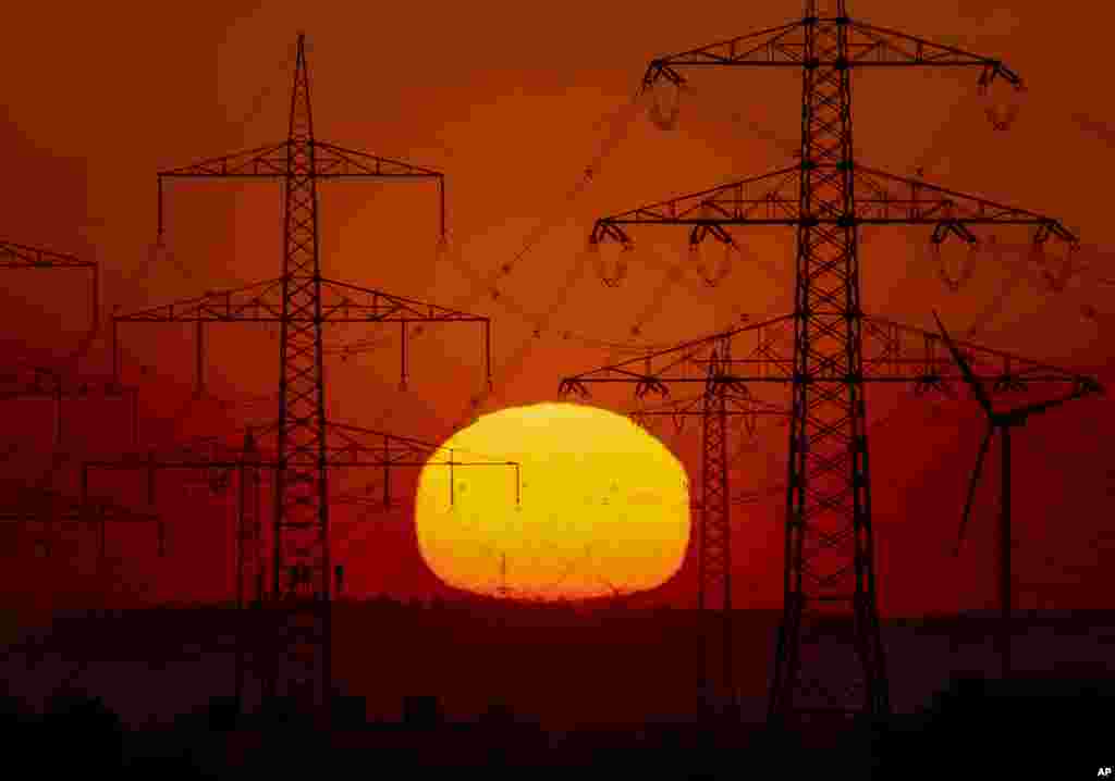 The sun rises behind power poles in the outskirts of Frankfurt, Germany.