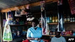 Virginia Mutsamwira, 52 ans, infirmière en chef, regarde une petite épicerie qu'elle tient chez elle, où elle vend également des poulets et des lapins pour compléter ses revenus d'infirmière, à Harare, le 25 avril 2022.