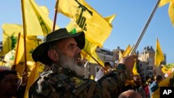 FILE - A Hezbollah fighter waves his group's flag as he attends an election rally in a southern suburb of Beirut, Lebanon, May 10, 2022.