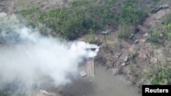 Smoke rises from what appears to be a makeshift bridge across the Siversky Donets River, eastern Ukraine, in this handout image uploaded May 12, 2022. (Ukrainian Airborne Forces Command/via Reuters)